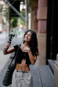 Smiling woman taking a selfie with smartphone on a city street.